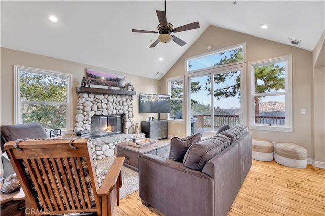 living room featuring a fireplace, ceiling fan, vaulted ceiling, and light hardwood / wood-style floors