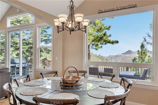 dining room with a mountain view, vaulted ceiling, and a chandelier