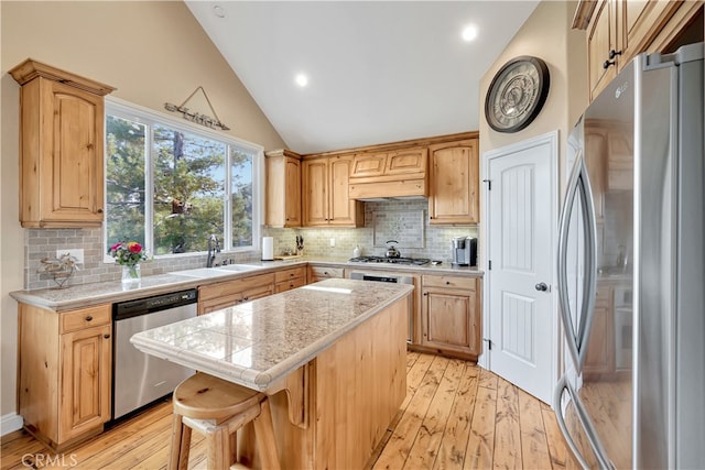 kitchen featuring light wood-type flooring, a breakfast bar, sink, appliances with stainless steel finishes, and a center island