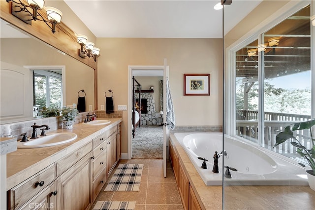 bathroom featuring tiled tub, vanity, and tile patterned flooring