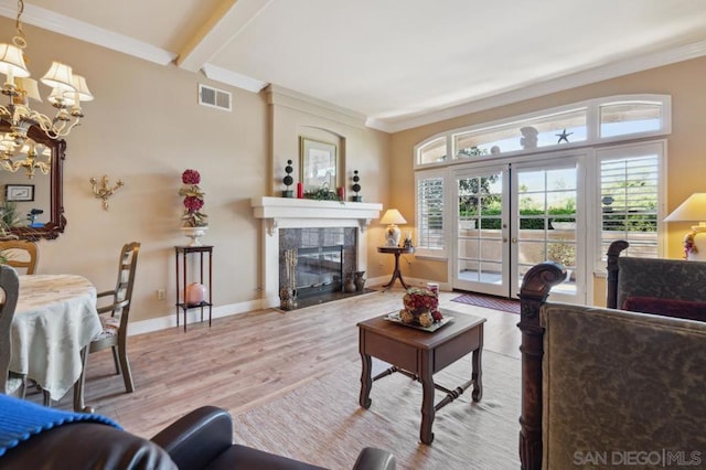 living room with french doors, a high end fireplace, crown molding, light hardwood / wood-style flooring, and a chandelier