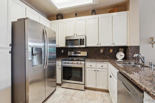 kitchen featuring white cabinetry, stainless steel appliances, sink, and dark stone counters