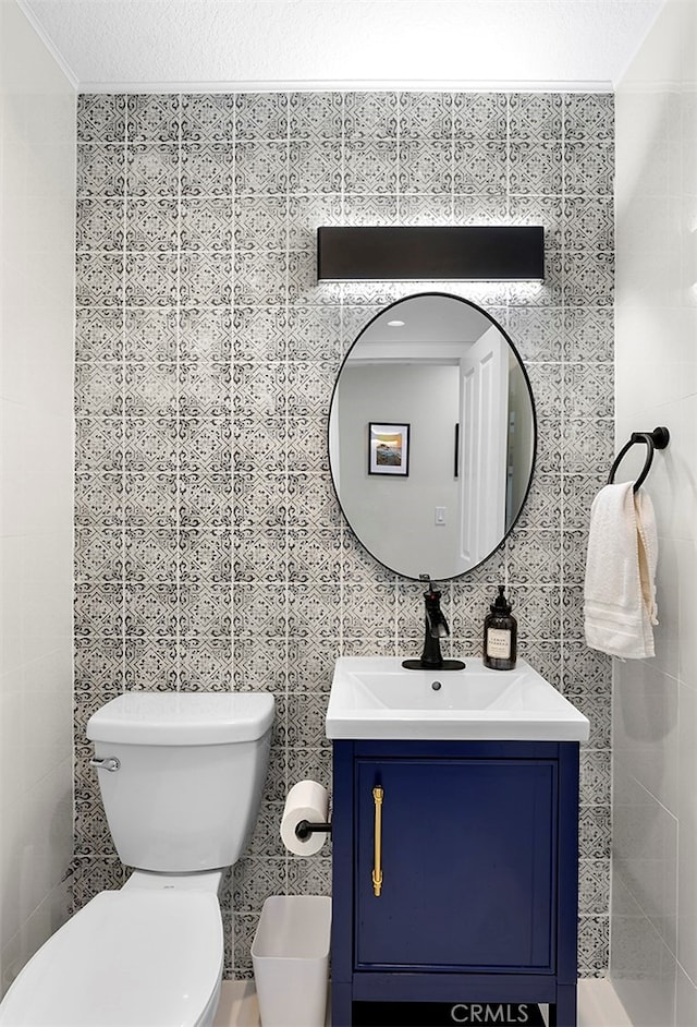 bathroom featuring vanity, tile walls, toilet, and a textured ceiling