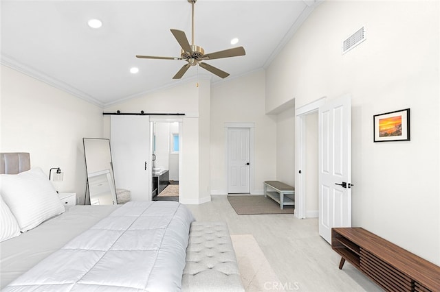 bedroom featuring ceiling fan, connected bathroom, light hardwood / wood-style floors, crown molding, and a barn door