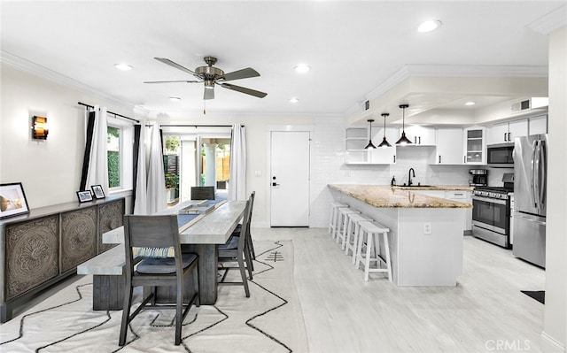 dining space with ceiling fan, sink, light hardwood / wood-style floors, and ornamental molding