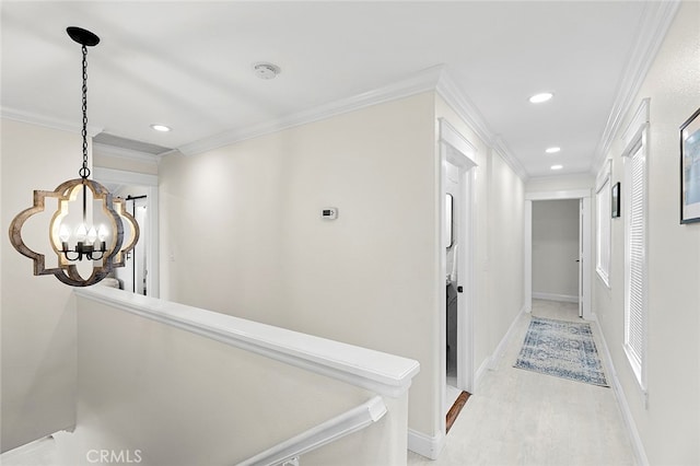 corridor featuring light wood-type flooring, crown molding, and a chandelier