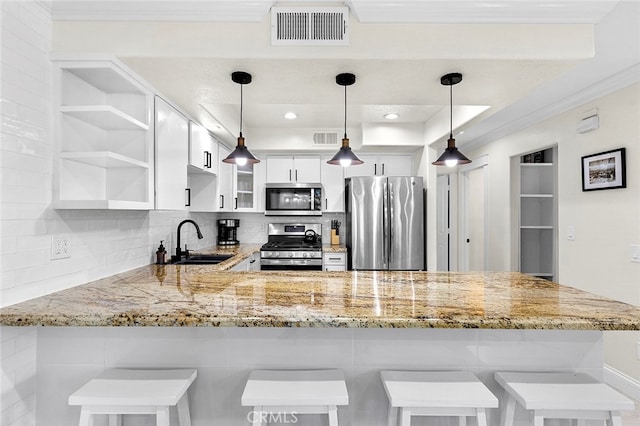 kitchen featuring a breakfast bar, sink, kitchen peninsula, white cabinetry, and appliances with stainless steel finishes