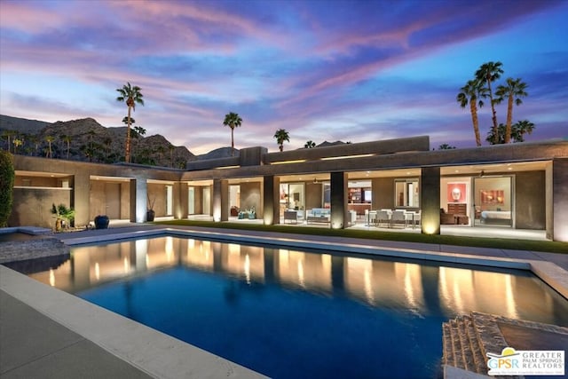 pool at dusk with a patio area and a mountain view