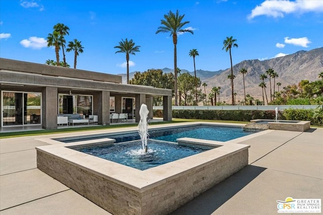 view of pool featuring an in ground hot tub, a patio area, and a mountain view