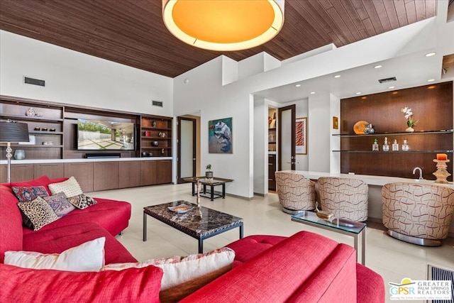 living room featuring built in shelves, bar, wood ceiling, and a high ceiling