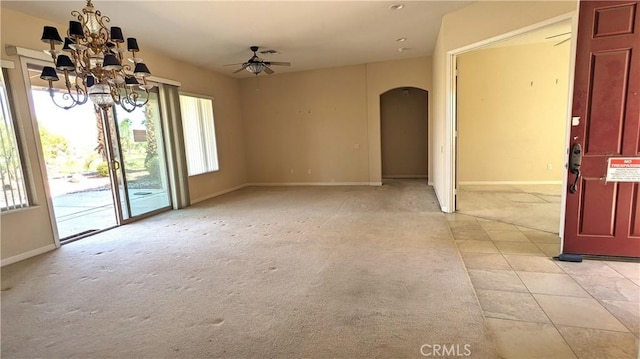 carpeted empty room with ceiling fan with notable chandelier