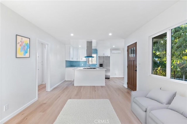 kitchen featuring stainless steel fridge, ventilation hood, light hardwood / wood-style flooring, a center island, and white cabinetry