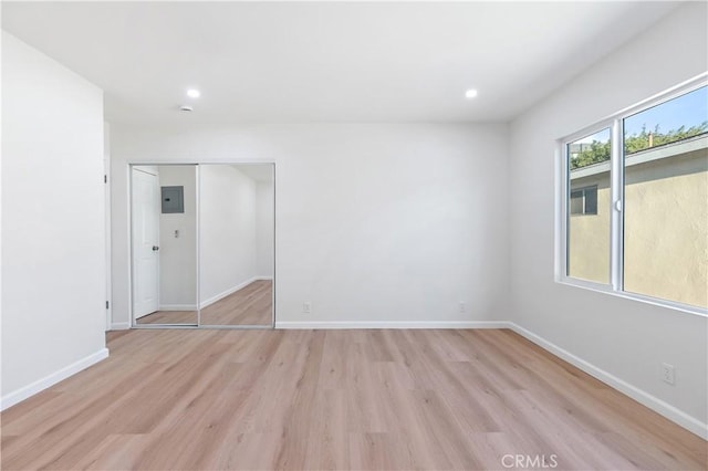 spare room with electric panel and light wood-type flooring