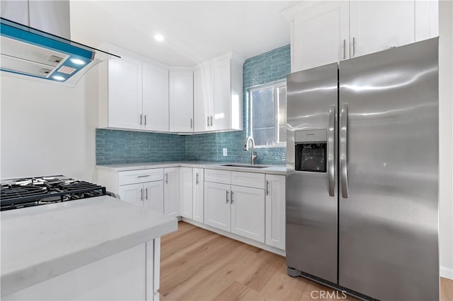 kitchen featuring exhaust hood, white cabinets, sink, stainless steel fridge, and light hardwood / wood-style floors