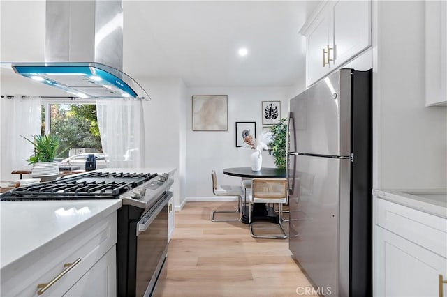 kitchen featuring white cabinetry, light stone countertops, wall chimney exhaust hood, light hardwood / wood-style flooring, and appliances with stainless steel finishes