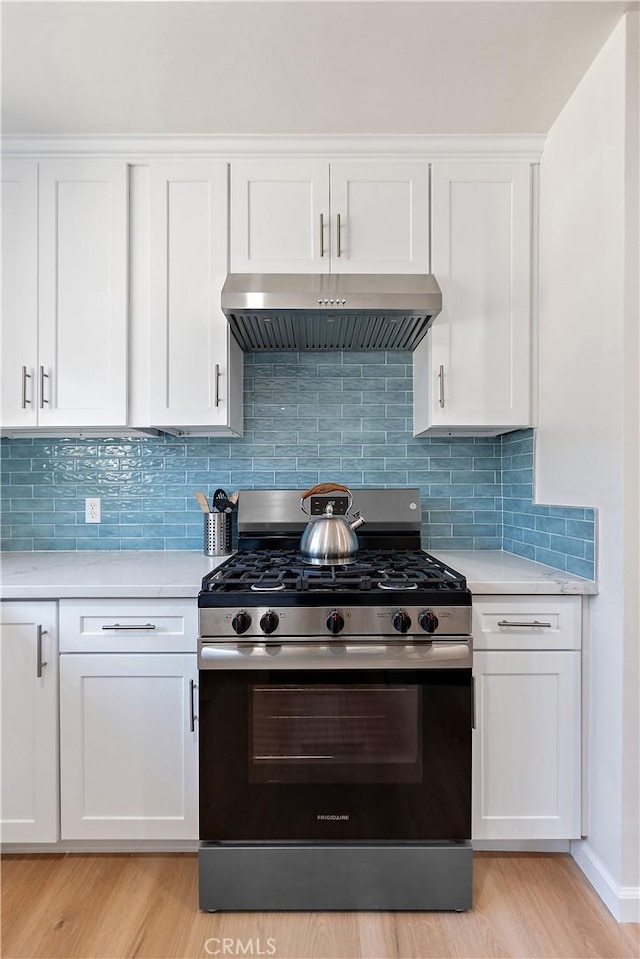 kitchen with decorative backsplash, gas stove, light hardwood / wood-style floors, and white cabinetry