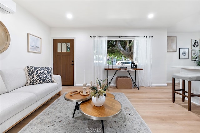 living room with a wall mounted AC and light hardwood / wood-style floors