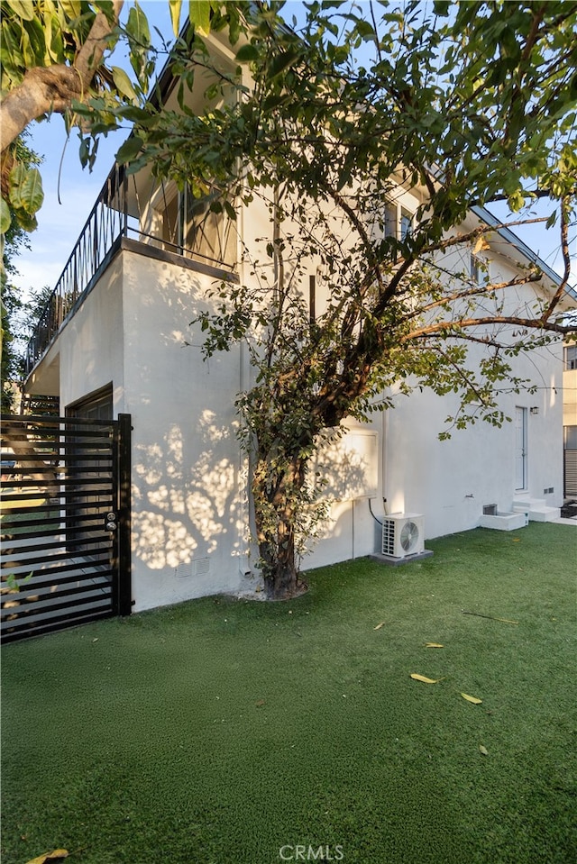 view of side of property with ac unit and a lawn