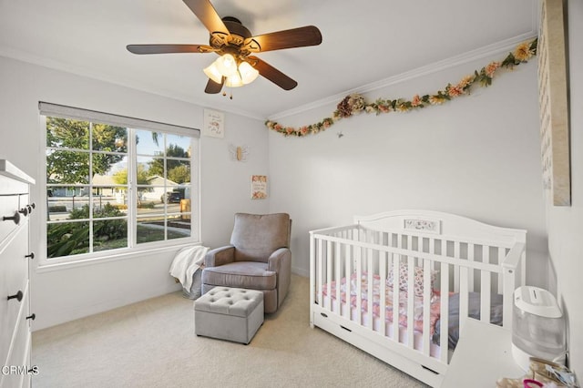 bedroom with light carpet, a nursery area, crown molding, and ceiling fan