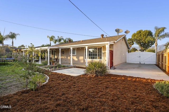 rear view of property featuring a trampoline and a patio