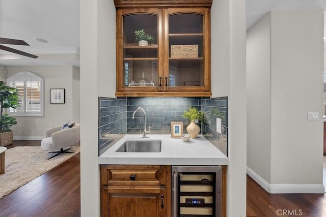 bar featuring dark wood-type flooring, beverage cooler, sink, and tasteful backsplash