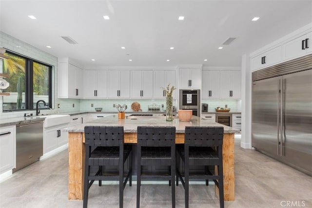 kitchen with a kitchen breakfast bar, a kitchen island, light stone counters, and stainless steel appliances