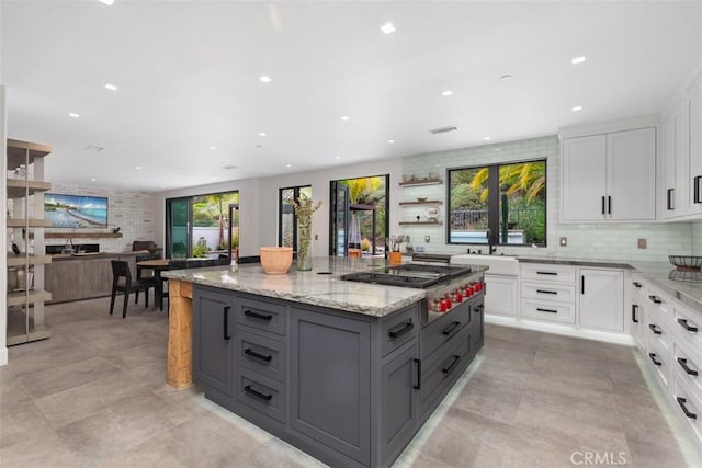 kitchen featuring white cabinets, a healthy amount of sunlight, gray cabinetry, and light stone countertops