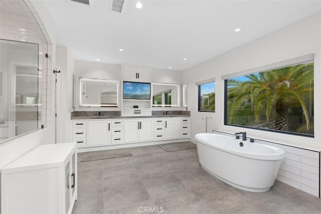 bathroom with a washtub, vanity, and tile walls