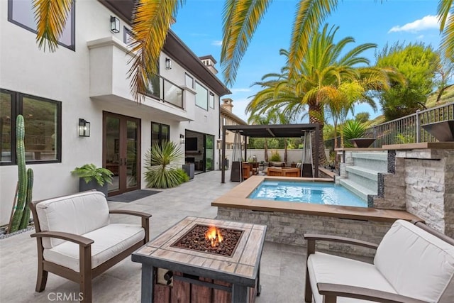 view of pool featuring french doors, an outdoor living space with a fire pit, and a patio