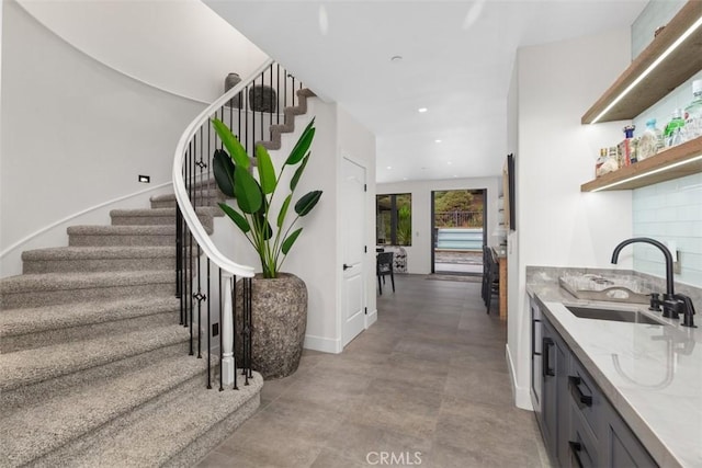 interior space with gray cabinetry, decorative backsplash, light stone counters, and sink