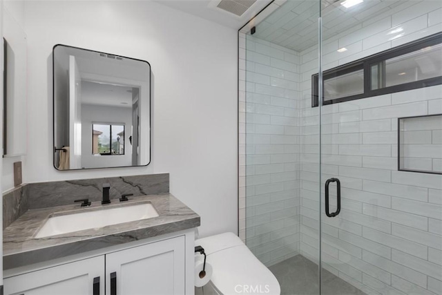 bathroom with vanity, toilet, and a shower with shower door