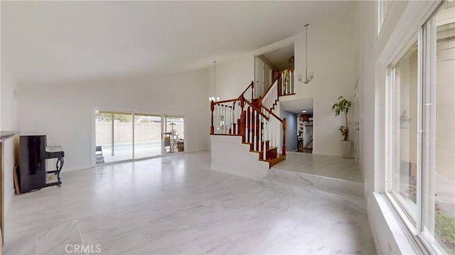 unfurnished living room featuring a chandelier and high vaulted ceiling