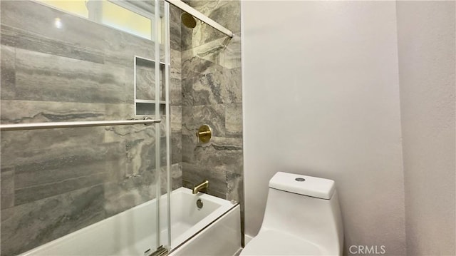 bathroom featuring toilet and bath / shower combo with glass door