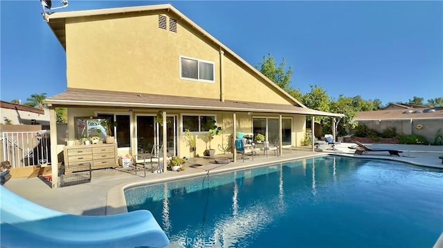 rear view of property featuring a patio area and a fenced in pool