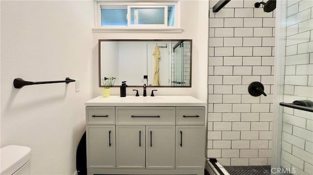 bathroom featuring vanity, a shower with shower door, and toilet