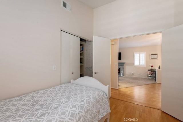 bedroom with a fireplace, a closet, and wood-type flooring