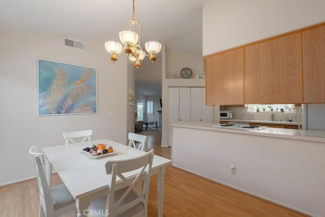 dining space with light hardwood / wood-style flooring, an inviting chandelier, and sink