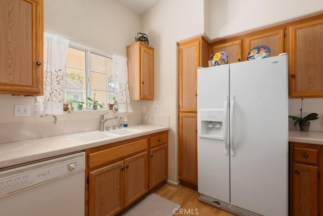 kitchen with light hardwood / wood-style floors, white appliances, and sink