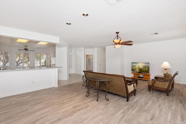 living room with ceiling fan and light hardwood / wood-style flooring