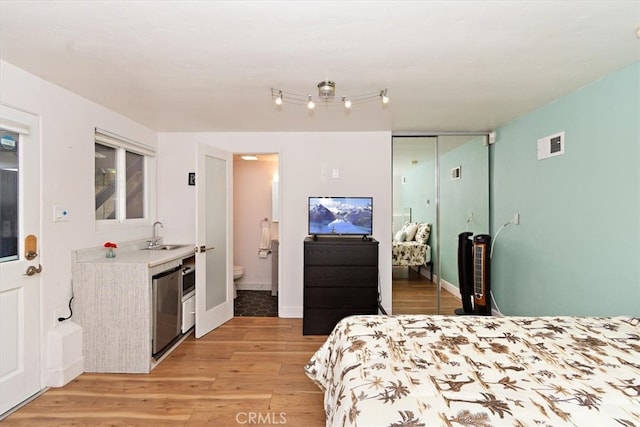 bedroom featuring light wood-type flooring, sink, ensuite bath, and a closet