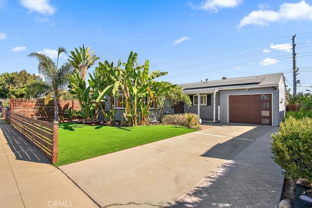 ranch-style home with a garage, solar panels, and a front lawn