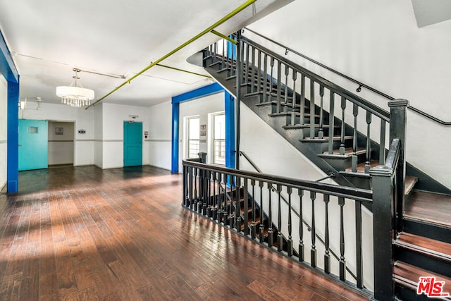 stairs with hardwood / wood-style floors and a notable chandelier