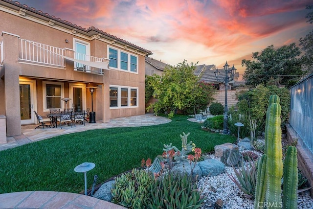 yard at dusk featuring a pergola, a patio area, and a balcony