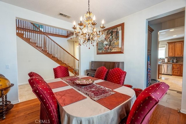 dining room with light hardwood / wood-style floors and an inviting chandelier