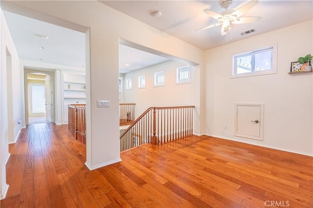 additional living space featuring ceiling fan, a healthy amount of sunlight, and light wood-type flooring