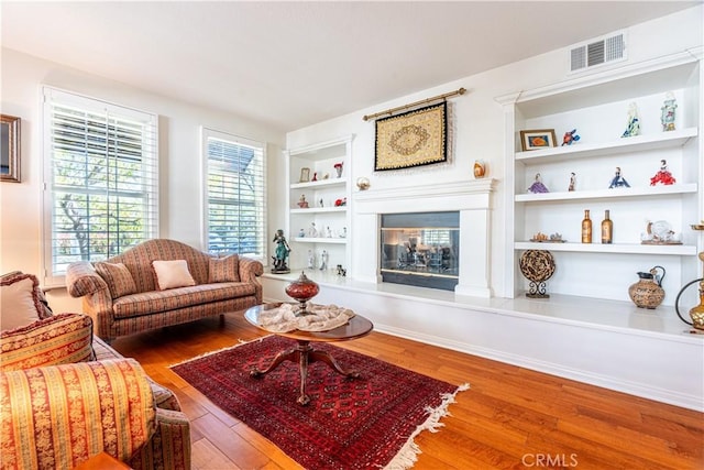 living room with hardwood / wood-style floors and built in shelves