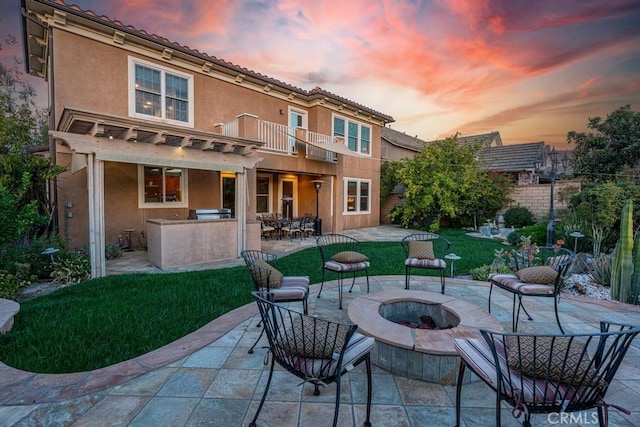 back house at dusk with a patio area, a balcony, area for grilling, and an outdoor fire pit