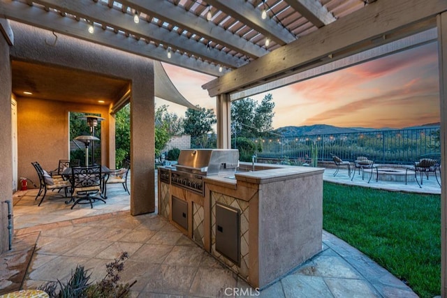 patio terrace at dusk featuring a pergola, area for grilling, and a mountain view