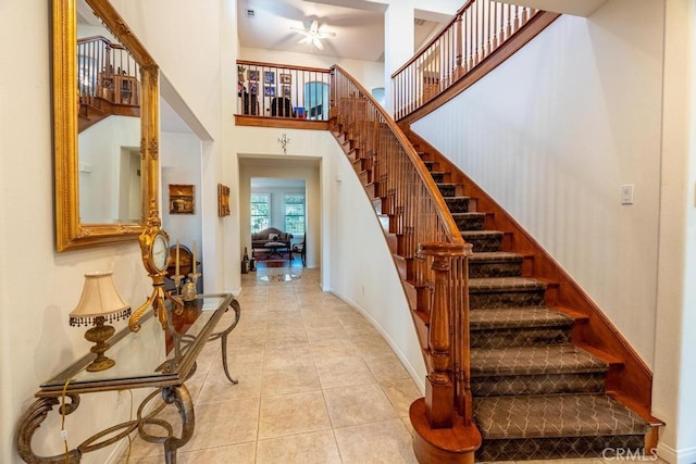 staircase featuring ceiling fan, tile patterned flooring, and a high ceiling