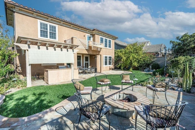 rear view of house with a lawn, a fire pit, a pergola, a balcony, and a patio